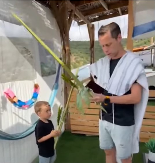 אבא מוטי ולביא הבן מנענעים לולב בסוכה.jpg