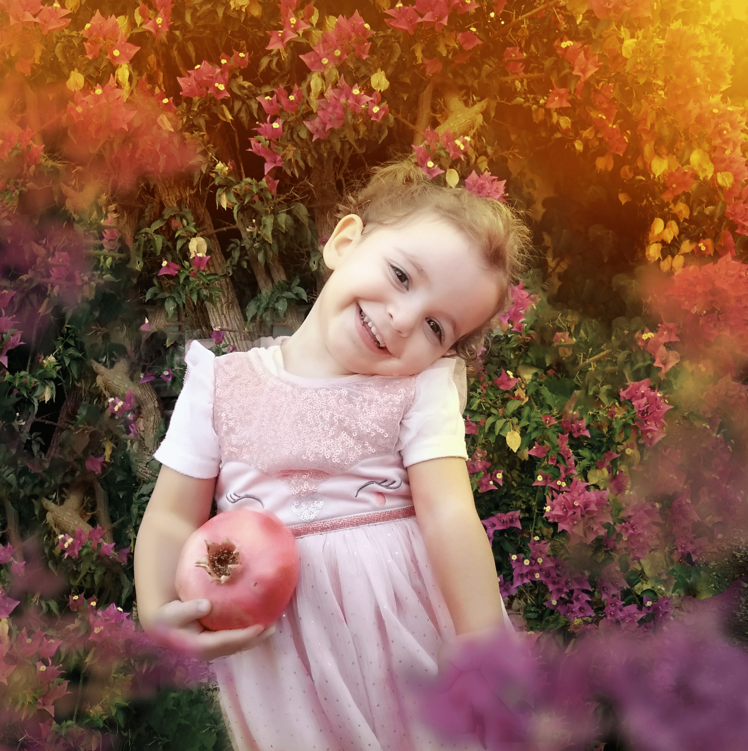 אילה מחזיקה רימון עם פרחים.png