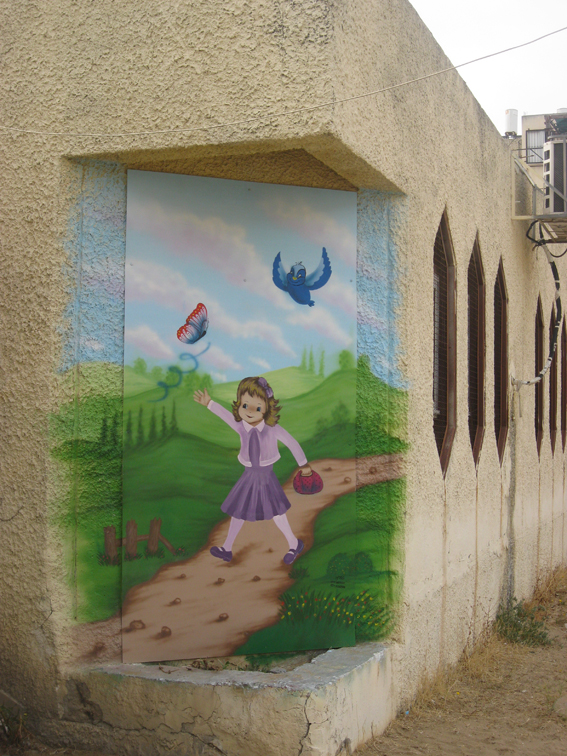 ציור חוץ רשת הגנים ,אשדוד.
הקיר ישן ובעל דוקרנים שמפריעים להנות מהציור.
לכן נעשה ברובו על דיקט שמוברג לקיר.